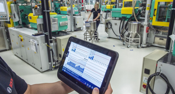 Ein Mitarbeiter der Robert Bosch GmbH überprüft mit einem Tablet die Betriebsdaten von vernetzten Maschinen für Metallspritzguss. (Foto: © dpa)
