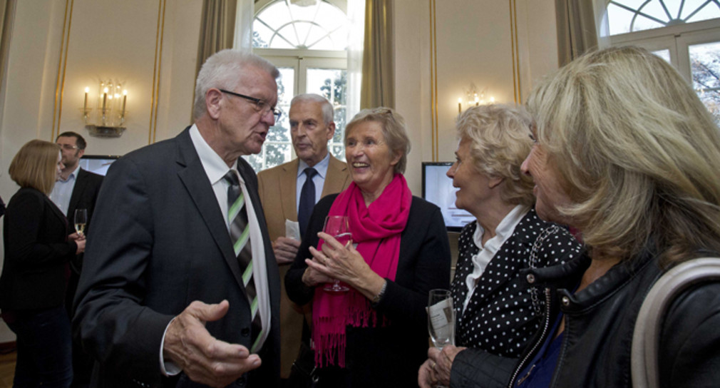 Ministerpräsident Winfried Kretschmann (l.) spricht im Runden Saal der Villa Reitzenstein mit Gästen. 