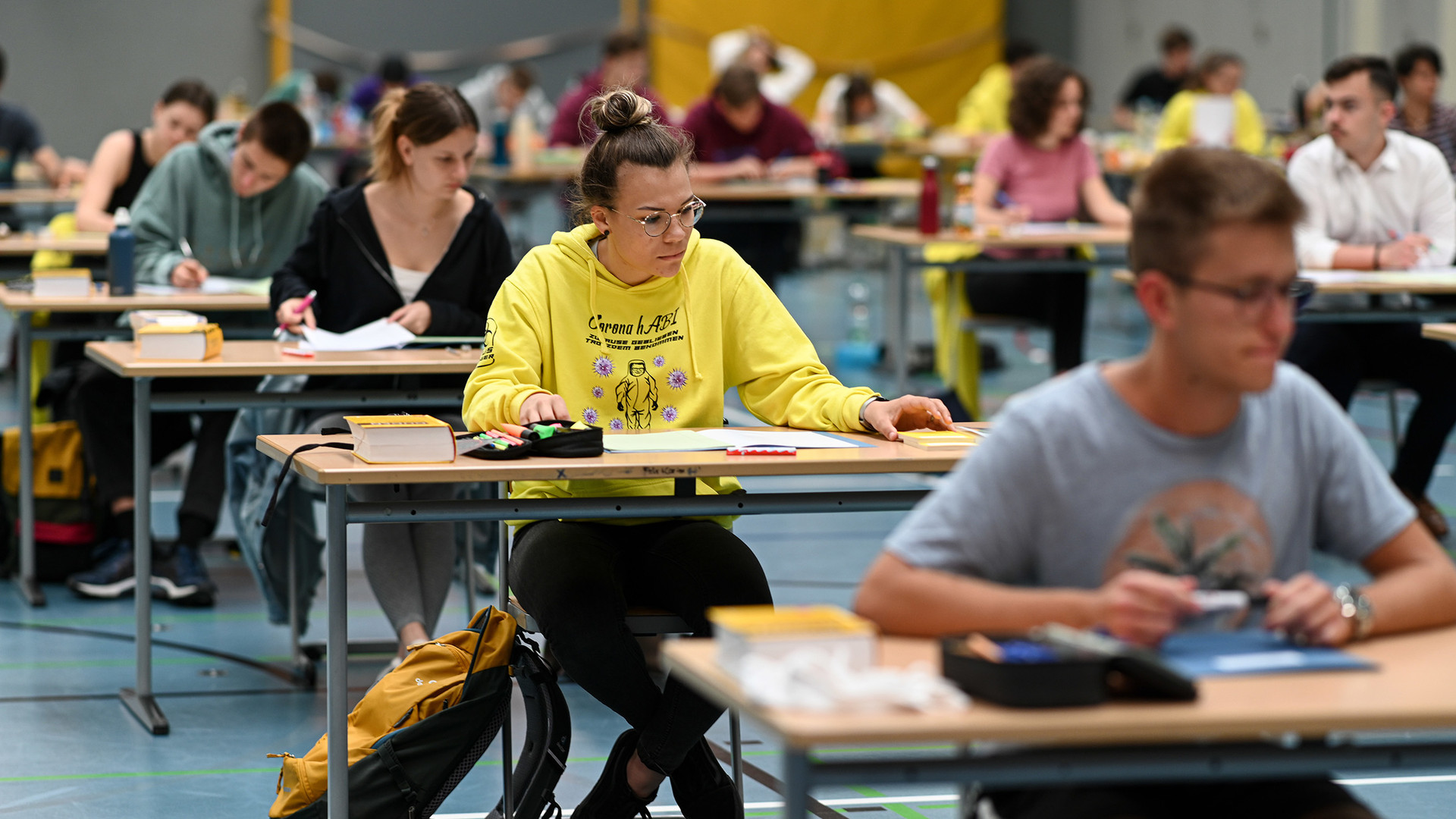 Schüler sitzen während der Deutsch-Abitursprüfung in einer Sporthalle. (Bild: © picture alliance/Felix Kästle/dpa)