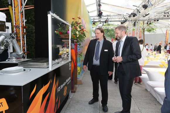 (R-L) Dipl.-Ing. Arne Rönnau vom Forschungszentrum Informatik (FZI) am Karlsruher Institut für Technologie (l.) und Staatssekretär Volker Ratzmann (r.) am Roboter-Bratwurststand