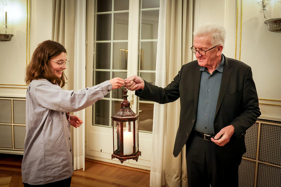 Eine Pfadfinderin (links) übergibt Ministerpräsident Winfried Kretschmann (rechts) das Friedenslicht.