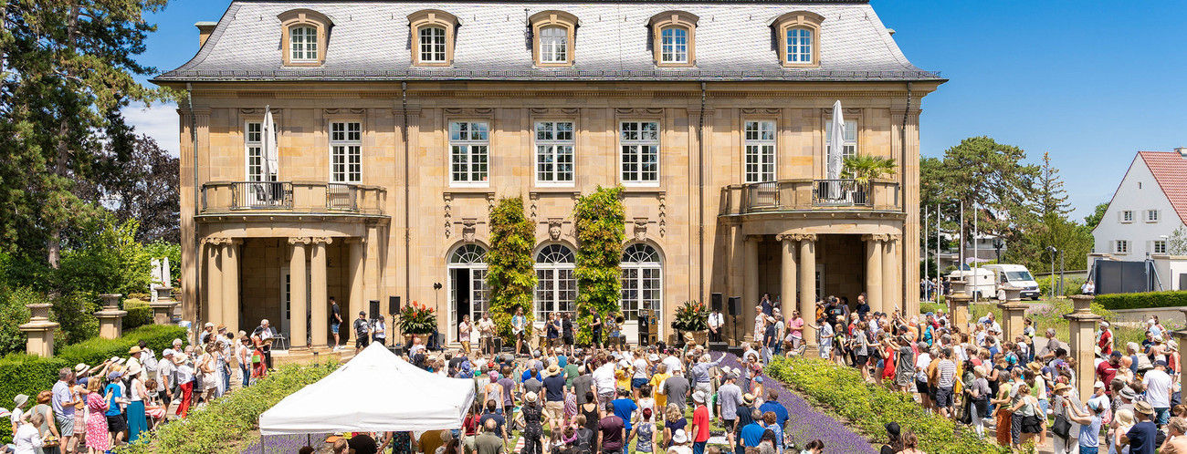 Im Rosengarten im Park der Villa Reitzenstein spielt eine Band vor Publikum.