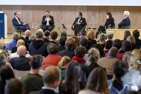 Podiumsdiskussion mit Prof. Dr. Markus Gabriel (links), The New Institute, Dr. Robert Habeck (Zweiter von links), Vizekanzler und Bundesminister für Wirtschaft und Klimaschutz, Moderator Peter Unfried (Mitte), Prof. Dr. Hedwig Richter (Zweite von rechts), Universität der Bundeswehr München, und Ministerpräsident Winfried Kretschmann (rechts)