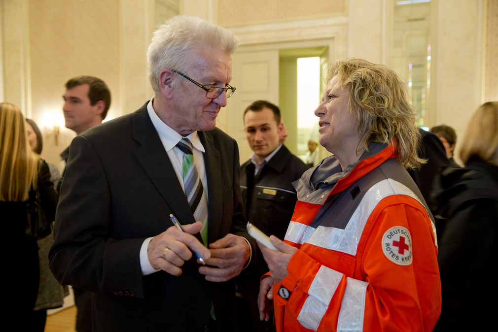 Ministerpräsident Winfried Kretschmann (l.) im Gespräch mit einer Helferin des Deutschen Roten Kreuzes