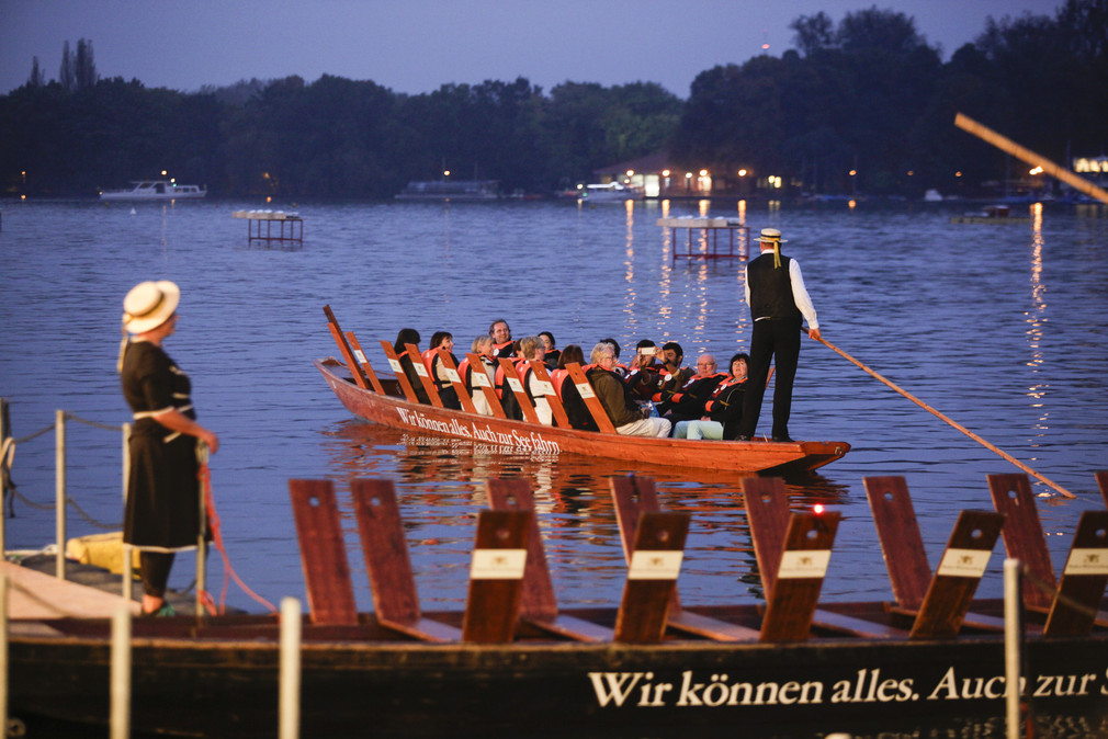 Besucher der Feierlichkeiten zum Tag der Deutschen Einheit in Hannover bei einer Stocherkahnfahrt in der Abenddämmerung.
