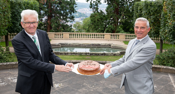 Ministerpräsident Winfried Kretschmann (l.) überreicht Innenminister Thomas Strobl (r.) eine Torte zum 75-jährigen Bestehen der CDU. (Bild: Staatsministerium Baden-Württemberg)