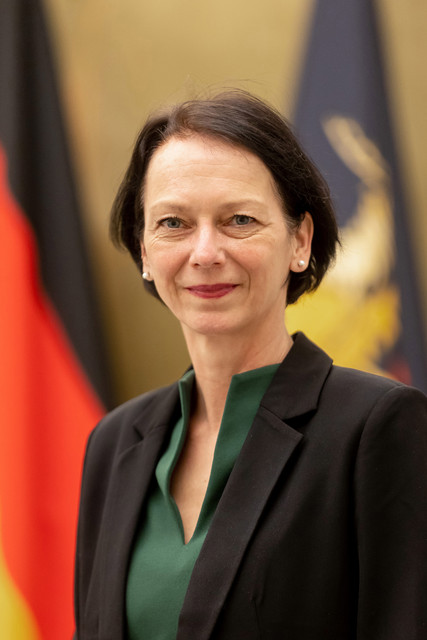 Susanne Bay steht vor Fahnen.