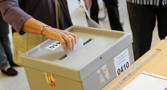 Eine Frau wirft ihren Wahlzettel in die Wahlurne (Bild: dpa).