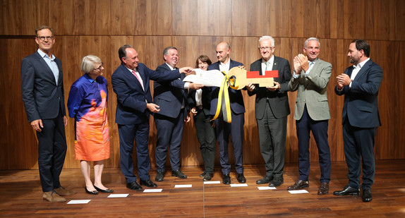 Gruppenbild auf der Bühne: Symbolische Schlüsselübergabe durch Ministerpräsident Winfried Kretschmann
