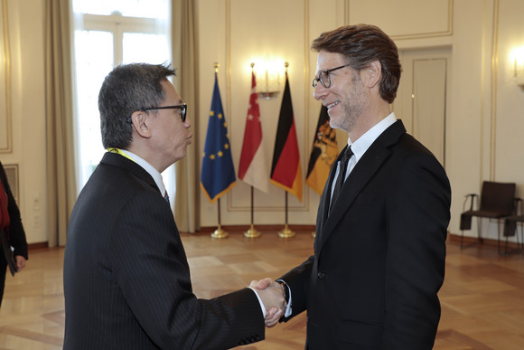 Internationales Stegmann empfängt Botschafter von Singapur Staatsminister Dr. Florian Stegmann (rechts) begrüßt den Botschafter der Republik Singapur, Lee Chong Hock (links). Im Hintergrund stehen Fahnen.