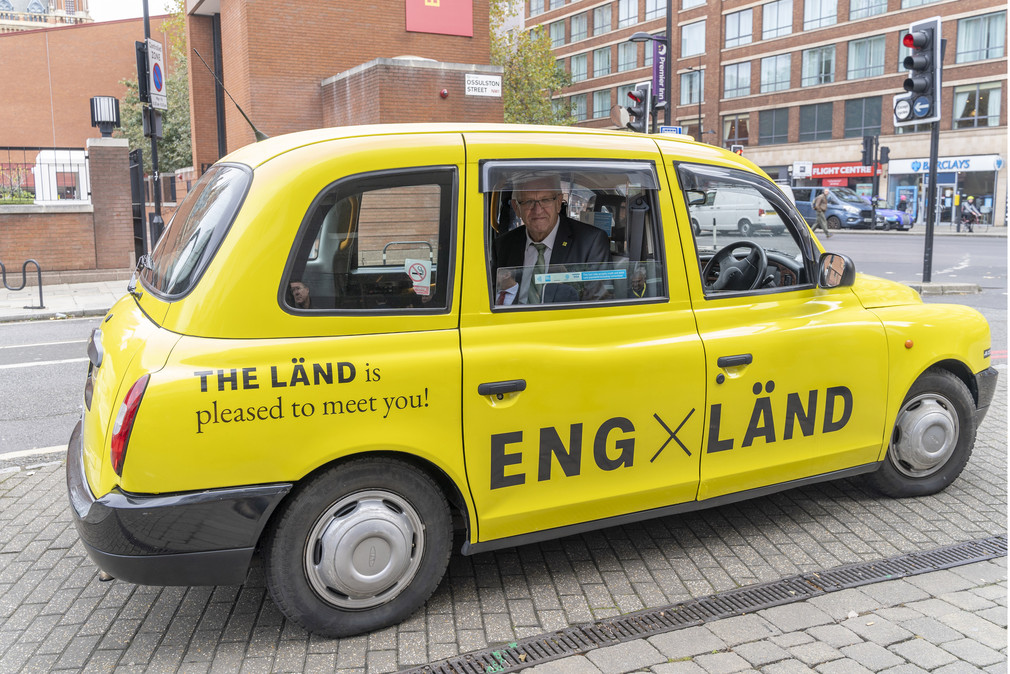 Ministerpräsident Winfried Kretschmann in einem Londoner Taxi im Design der neuen „THE LÄND“-Kampagne