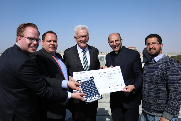 Ministerpräsident Winfried Kretschmann (M.) übergibt Pfarrer Mitri Raheb (2.v.r.) beim Besuch des Dar al-Kalima-College in Bethlehem einen Scheck zum Ausbau der Solaranlage des Colleges