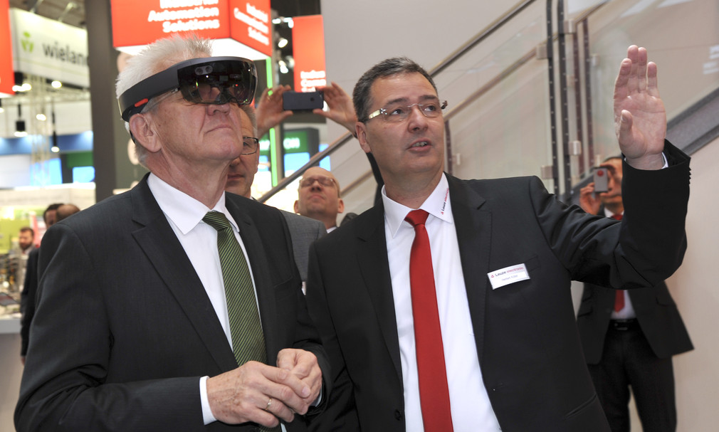 Ministerpräsident Winfried Kretschmann (l.) besucht den Stand der Leuze electric GmbH & Co. KG aus Owen