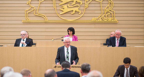 Ministerpräsident Kretschmann spricht am Rednerpult im Landtag von Baden-Württemberg (Bild: © dpa).