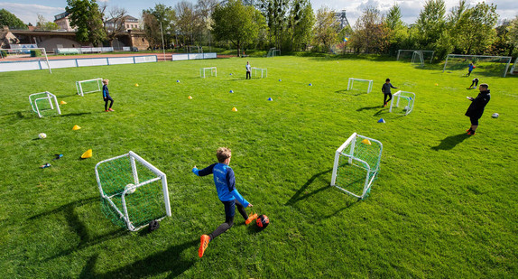 Fußballer der Altersklasse U-10 trainieren auf dem Spielfeld in großen Abständen. 