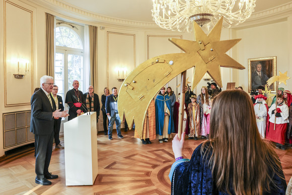 Ministerpräsident Winfried Kretschmann (links) spricht zu den Sternsingerinnen und Sternsingern.