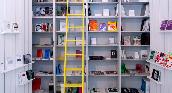 Eine gelbe Leiter steht vor einem Bücherregal