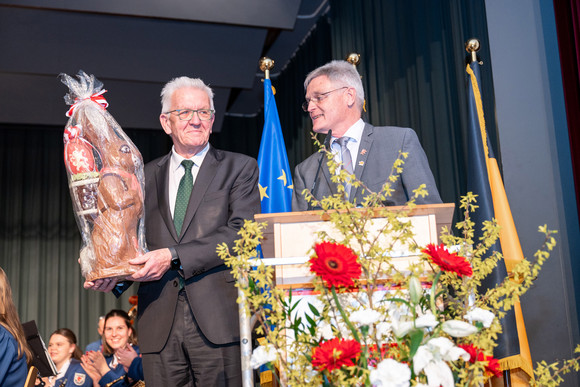 Ministerpräsident Winfried Kretschmann (links) mit einem großen Schokoladen-Osterhasen und Achim Deinet (rechts), Bürgermeister von Bad-Schussenried