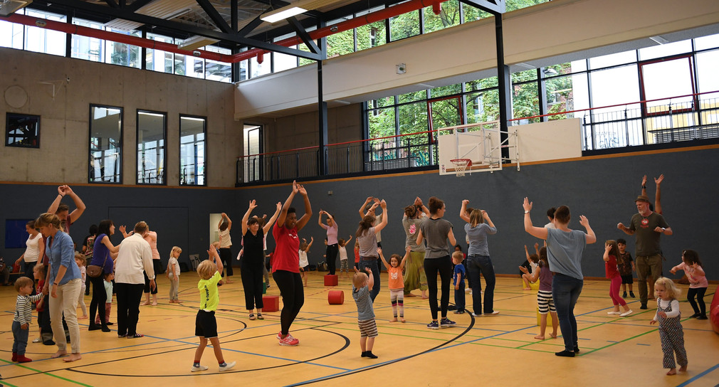 Eltern und Kinder turnen in einer Sporthalle in Berlin.