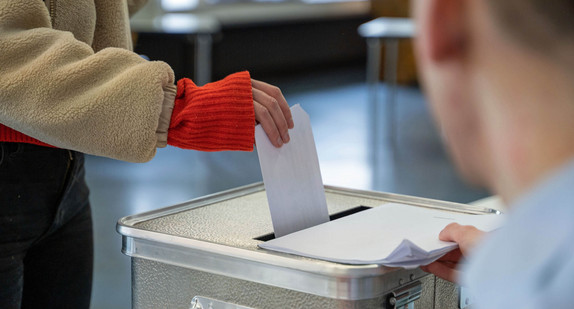 Eine Frau steckt ihren Stimmzettel für die Bundestagswahl in einem Wahllokal in eine Wahlurne.