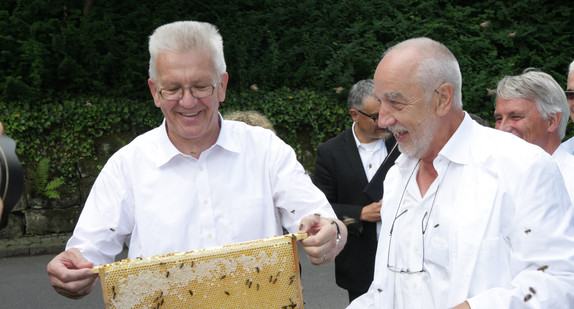 Ministerpräsident Winfried Kretschmann betrachtet Bienenwaben. Rechts von ihm steht Dr. Helmut Horn von der Landesanstalt für Bienenkunde.