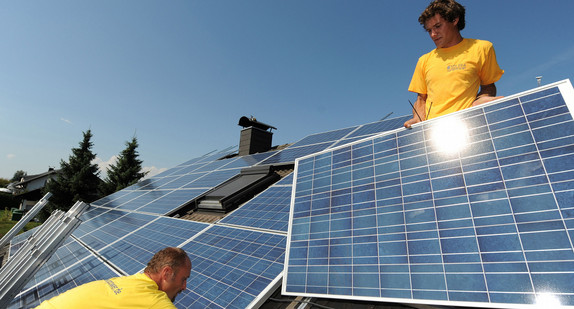 Zwei Monteure einer Firma für Solartechnik installieren auf einem Dach Solarpanele. (Bild: © dpa)