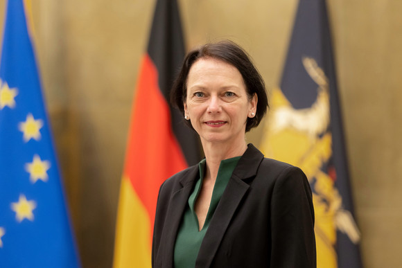 Susanne Bay steht vor Fahnen.