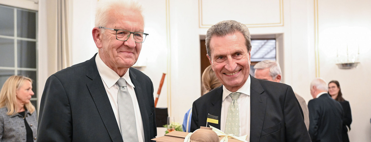Ministerpräsident Winfried Kretschmann (links) überreicht dem ehemaligen Ministerpräsidenten Günther Oettinger (rechts) bei einem Empfang anlässlich dessen 70. Geburtstages ein Bienenhotel in Form der Villa Reitzenstein.