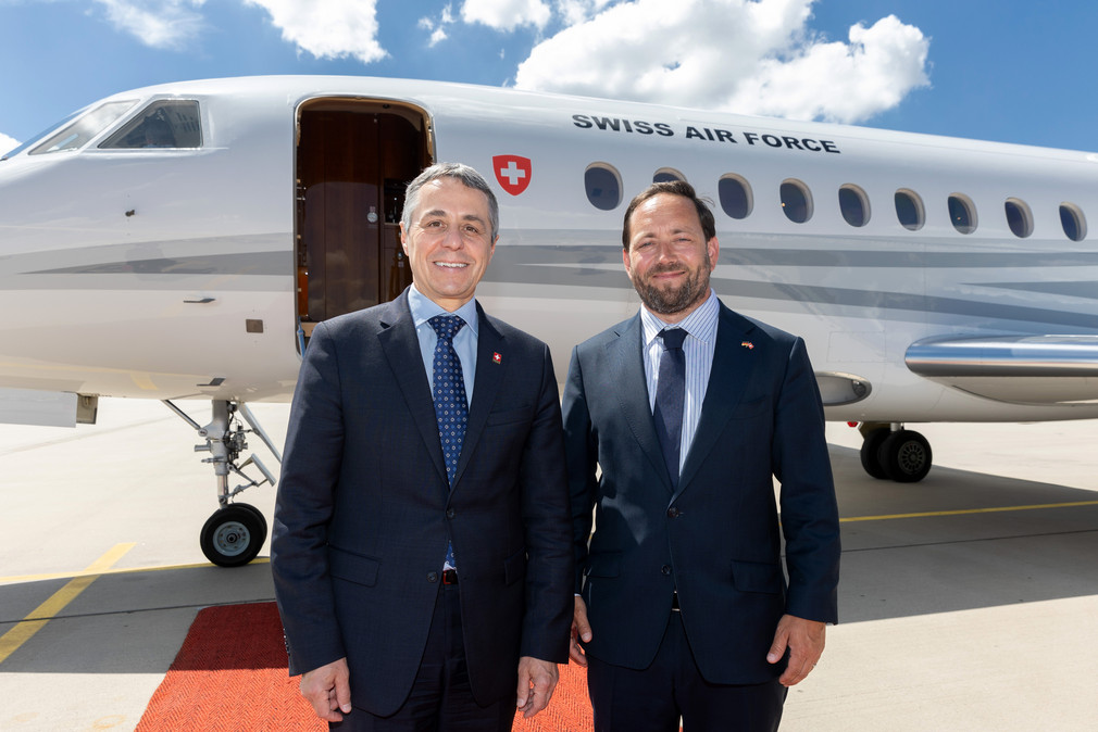 Staatssekretär Florian Hassler (rechts) und der Schweizer Bundespräsident Ignazio Cassis (links) stehen am Stuttgarter Flughafen vor einem Flugzeug.