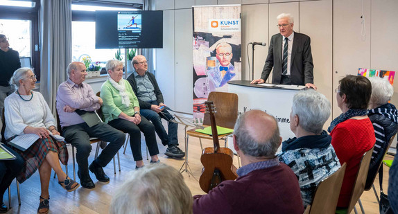 Ministerpräsident Winfried Kretschmann (stehend) bei seiner Ansprache beim Besuch des KUNSTschalters Schemmerhofen.