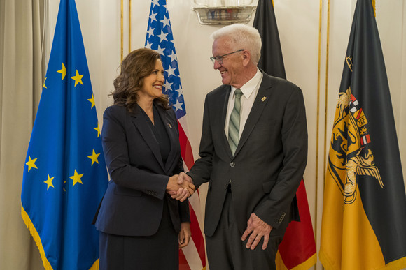 Ministerpräsident Winfried Kretschmann (rechts) und die Gouverneurin von Michigan, Gretchen Whitmer (links), stehen in der Villa Reitzenstein vor Fahnen.