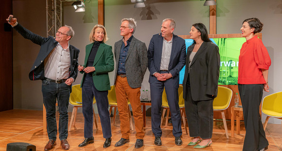 Machen zusammen ein Selfie auf der Bühne: Kai Gniffke, Julia Jäkel, Rudi Hoogvliet, Stephan Schmitter, Yasmine M'Barek und Elena Kountidou. Herr Gniffke hält dafür sein Mobiltelefon hoch.