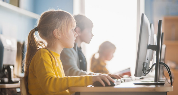 Kinder sitzen im Unterricht an Computern.