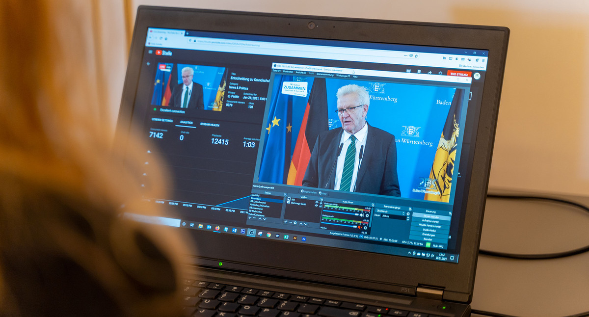 Auf einem Computer läuft ein Livestream einer Pressekonferenz mit Ministerpräsident Kretschmann.