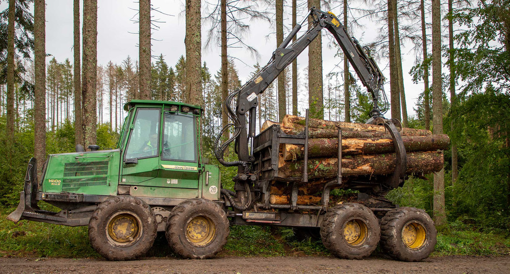 Auf einem Waldweg steht ein spezielles Räumfahrzeug um geschlagenes Holz aus dem Wald zu transportieren.
