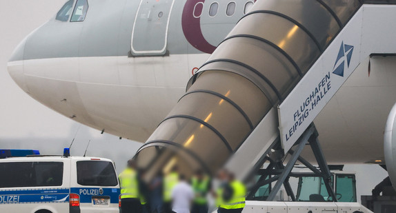 Menschen besteigen ein Flugzeug. Vor dem Fahrzeug der Bundespolizei stehen auf dem Vorfeld am Flughafen Leipzig/Halle.
