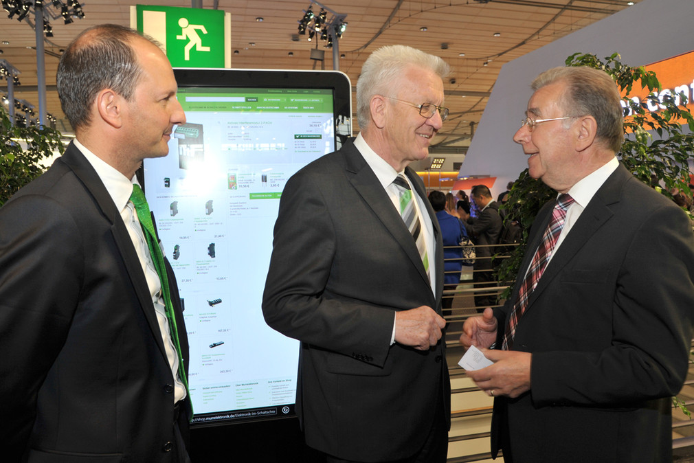 Ministerpräsident Winfried Kretschmann (M.) mit Franz Hafner (r.), Firmengründer von Murrelektronik und Geschäftsführer Stefan Grotzke (l.) am Stand der Murrelektronik GmbH