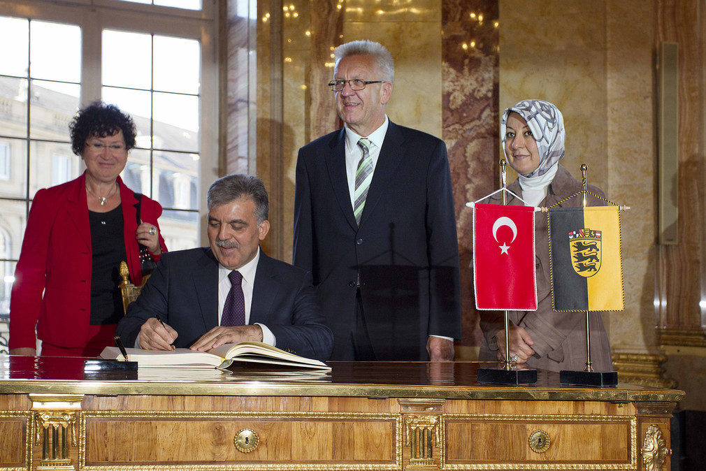 Der türkische Staatspräsident Abdullah Gül trägt sich in das Gästebuch des Landes Baden-Württemberg ein. Hinter ihm stehen v.l.n.r.: Gerlinde Kretschmann, Ministerpräsident Winfried Kretschmann und Hayrünnisa Gül.