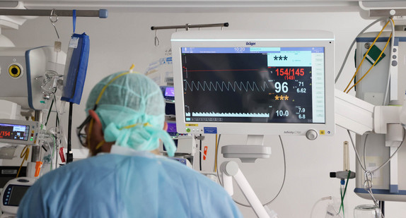 Ärzte und Pfleger untersuchen einen Patienten auf einer Covid-19 Intensivstation.