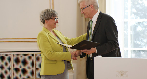 Ministerpräsident Winfried Kretschmann (r.) überreicht Ministerin Silke Krebs (l.) die Entlassungsurkunde.