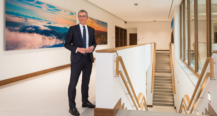 Bodo Lehmann vor Bildern an Treppe im Forum des Erweiterungsbaus der Landesvertretung in Brüssel. 