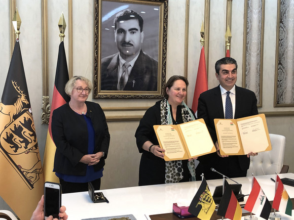 Staatsministerin Theresa Schopper (M.) und der Gouverneur des Gouvernements Dohuk, Farhad Atrushi (r.), bei der Unterzeichnung eines Kooperationsabkommens im Bereich der humanitären Hilfe mit dem Land Baden-Württemberg, daneben Wissenschaftsministerin Theresia Bauer (l.) (Bild: Staatsministerium Baden-Württemberg)