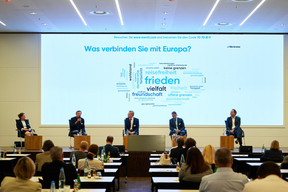 Auf einer Bühne diskutieren die Beteiligten der Podiumsdiskussion der Festveranstaltung „EUropa – Gestern. Heute. Morgen.“