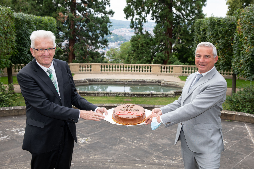 Ministerpräsident Winfried Kretschmann (l.) überreicht Innenminister Thomas Strobl (r.) eine Torte zum 75-jährigen Bestehen der CDU. (Bild: Staatsministerium Baden-Württemberg)