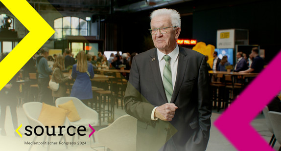 Ministerpräsident Kretschmann steht lächelnd in einer großen Halle. Im Hintergrund Menschen. Er wird eingerahmt von einem gelben und einem pinken Pfeil, dem Logo des Kongresses. Text: "source. Medienpolitischer Kongress 2024"