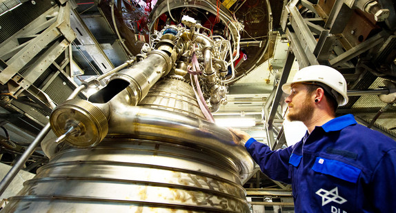 Ein Prüfstandshandwerker begutachtet am Deutschen Zentrum für Luft- und Raumfahrt ein Raketen-Triebwerk