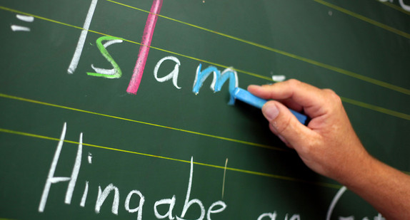 Ein Religionslehrer schreibt im Islamunterricht an die Tafel (Foto: © dpa)