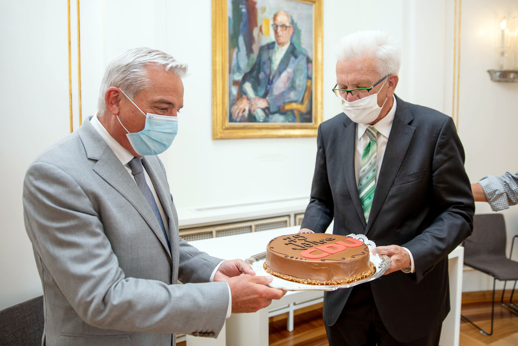 Ministerpräsident Winfried Kretschmann (r.) überreicht Innenminister Thomas Strobl (l.) eine Torte zum 75-jährigen Bestehen der CDU. (Bild: Staatsministerium Baden-Württemberg)