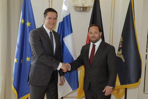 Staatssekretär Florian Hassler (rechts) und der finnische Botschafter Kai Jürgen Mikael Sauer (links) stehen vor Fahnen.