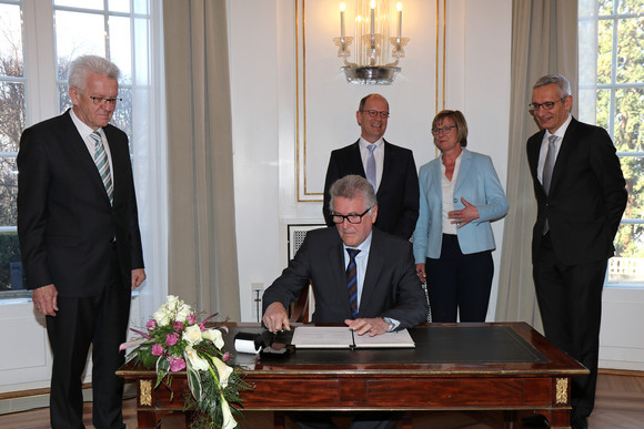 Volker Stich (sitzend), Vorsitzender des Beamtenbundes Baden-Württemberg, unterzeichnet die Vereinbarung; stehend v.l.n.r.: Ministerpräsident Winfried Kretschmann,  Matthias Grewe, Vorsitzender des Vereins der Richter und Staatsanwälte Baden-Württemberg e.V., Finanzministerin Edith Sitzmann und Staatssekretär Martin Jäger